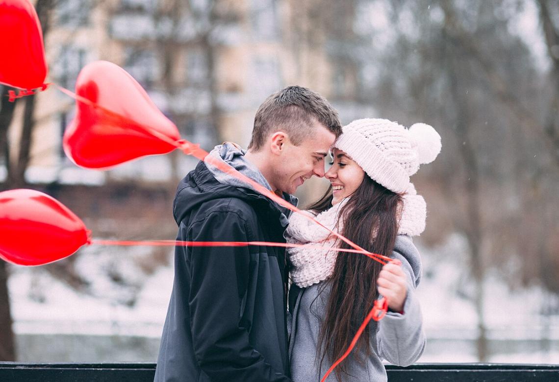 A smiling couple with heart shape baloons